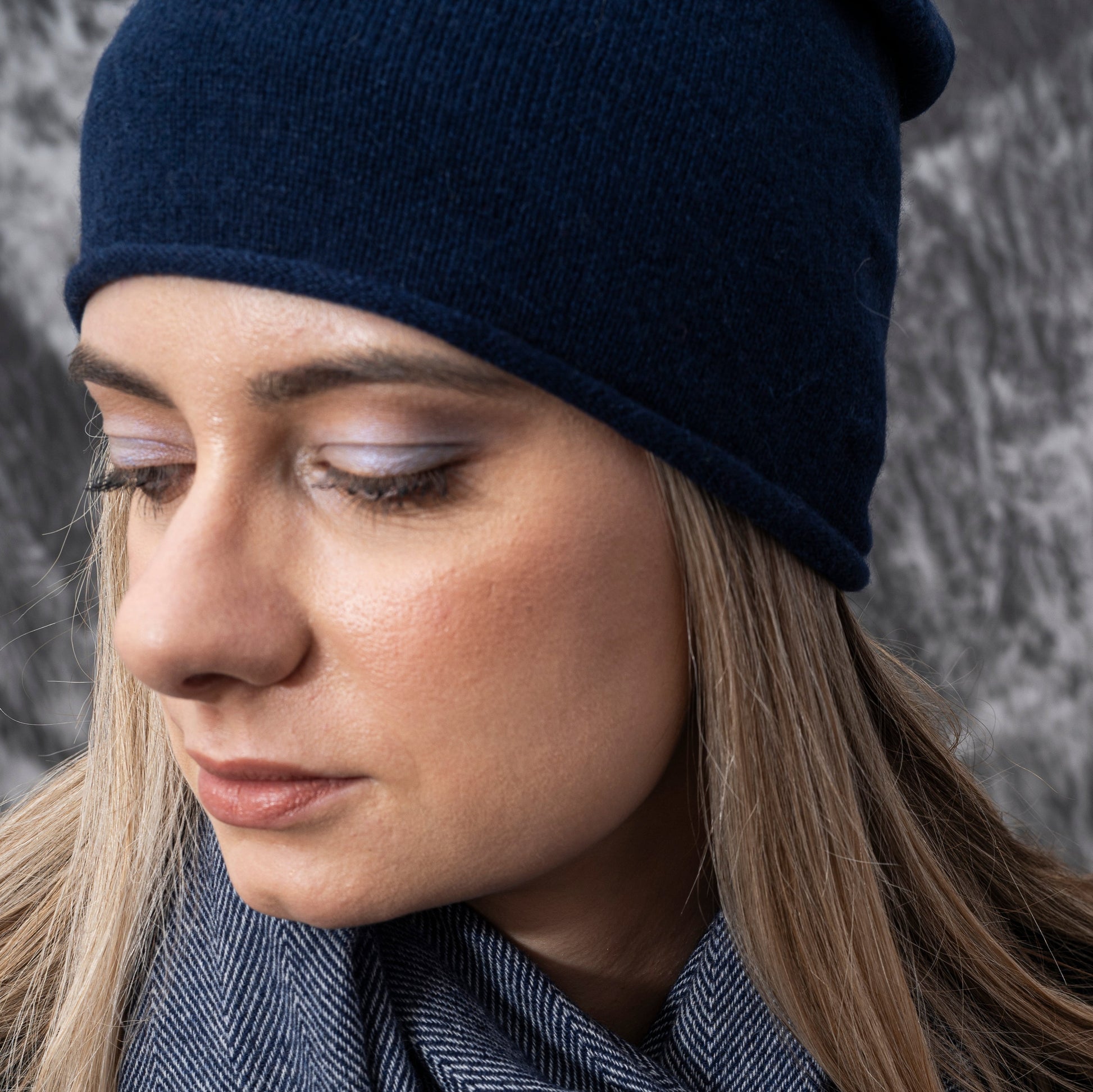 A closeup of a woman wearing cashmere Lightweight Reverse Knit Cap by Rayaa in Snow white color