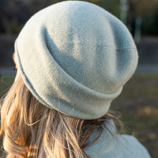 A closeup of a woman wearing cashmere Lightweight Reverse Knit Cap by Rayaa from behind