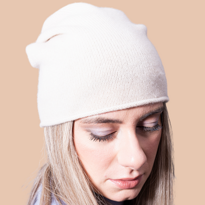 A closeup of a woman wearing cashmere Lightweight Reverse Knit Cap by Rayaa in Snow white color