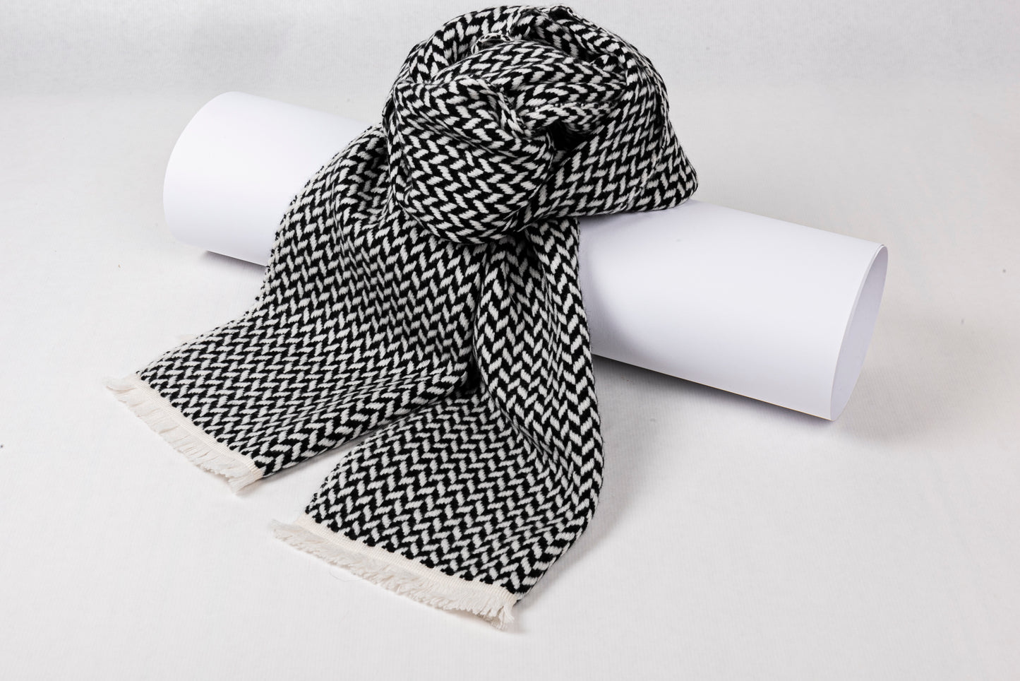 Cashmere Herringbone Narrow Shawl in black and white, draped elegantly on a rolled white surface.
