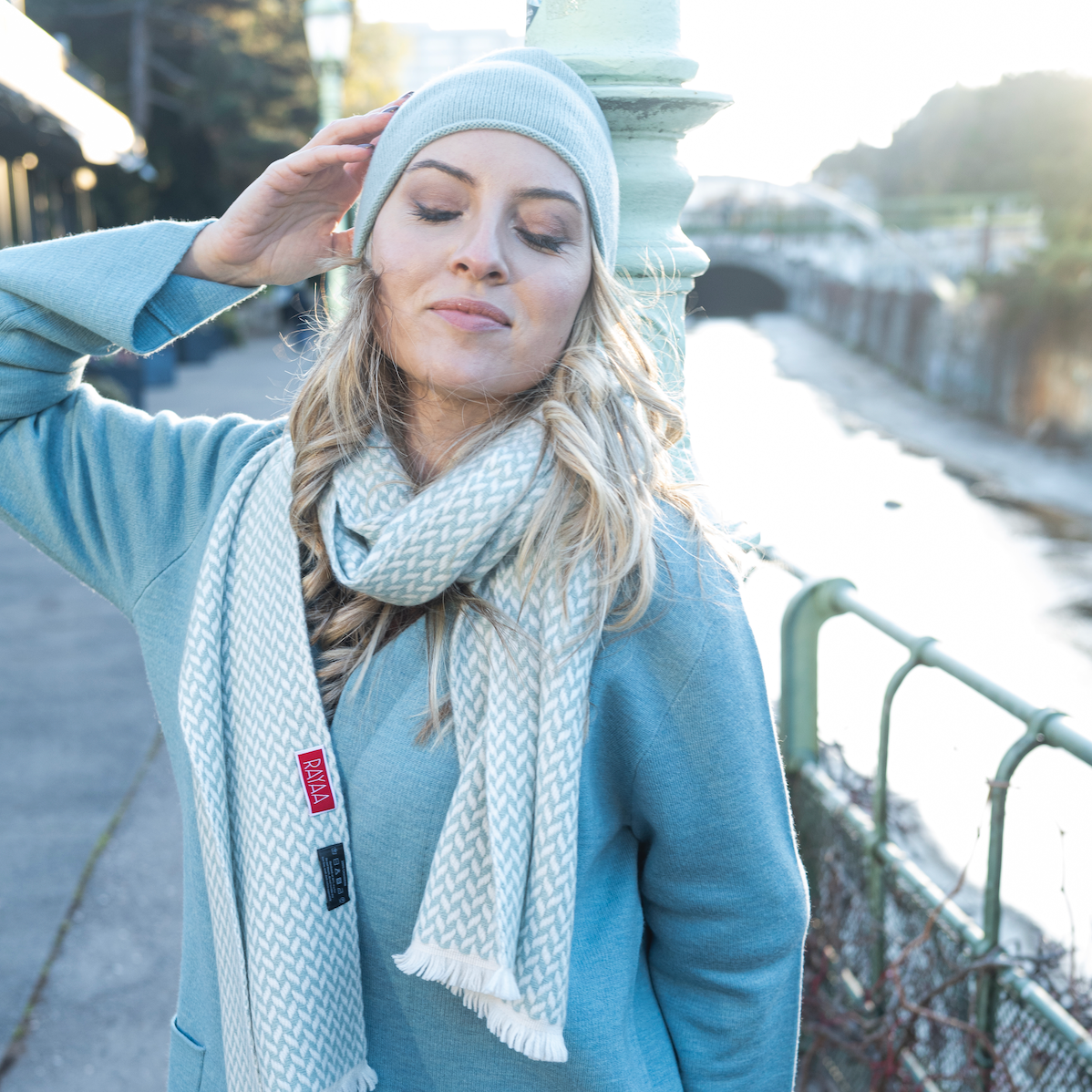 Woman enjoying the outdoors wearing a Cashmere Herringbone Narrow Shawl and matching hat, exuding casual elegance.